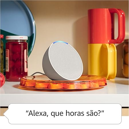 Echo Pop da Amazon com Alexa ativada em uma bancada de cozinha, ao lado de utensílios coloridos e potes, exibindo o comando de voz "Alexa, que horas são?".